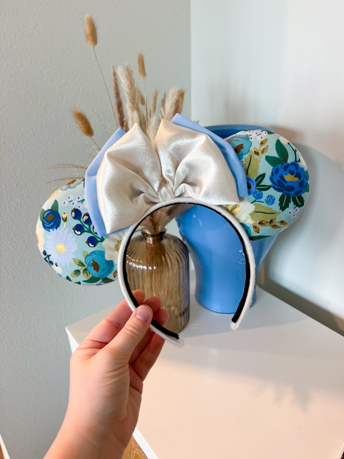 A pair of fabric ears featuring a blue floral pattern and a silky double bow.