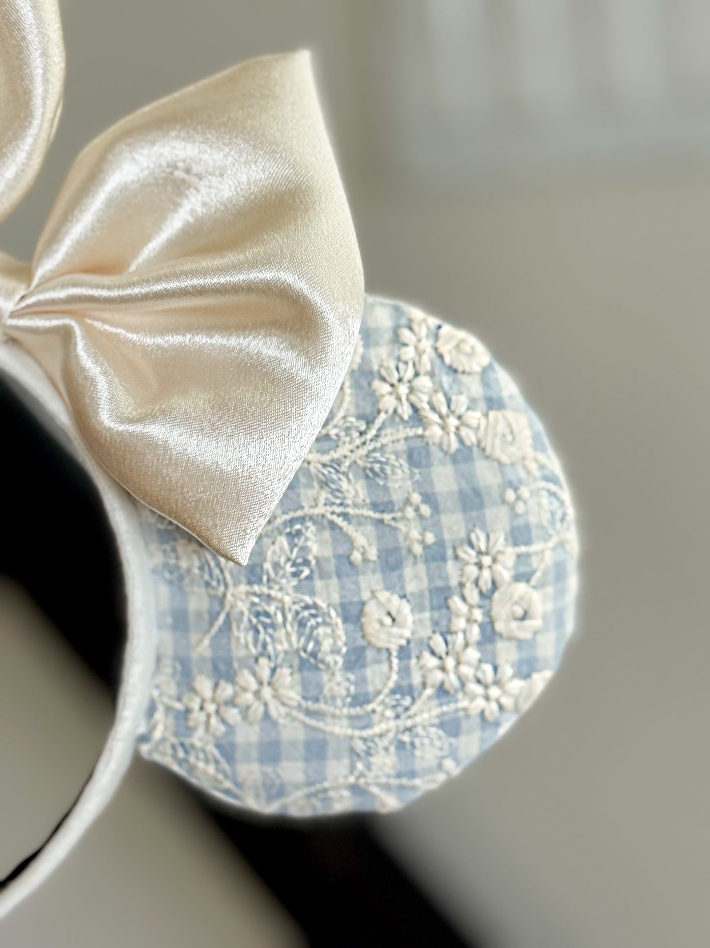 Decorative headband with a bow and floral lace design on a neutral background (this is a close up of the previous photo)