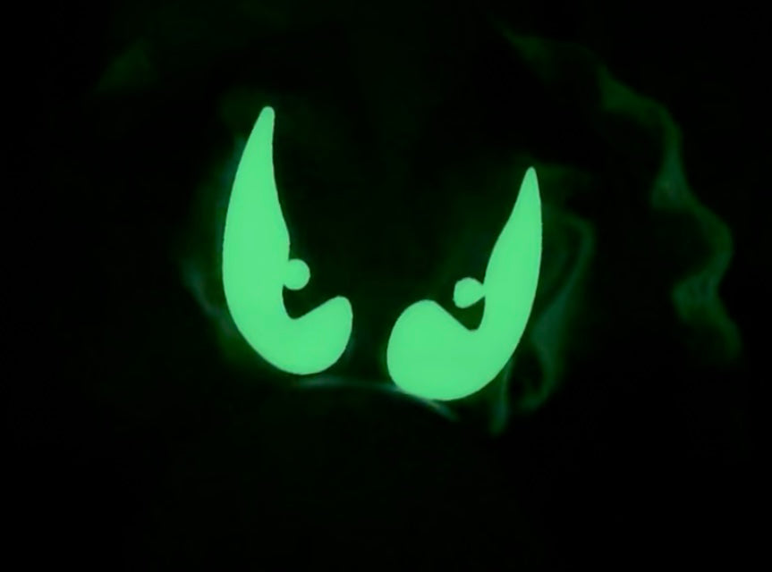 Glowing green bat eyes on a dark background
