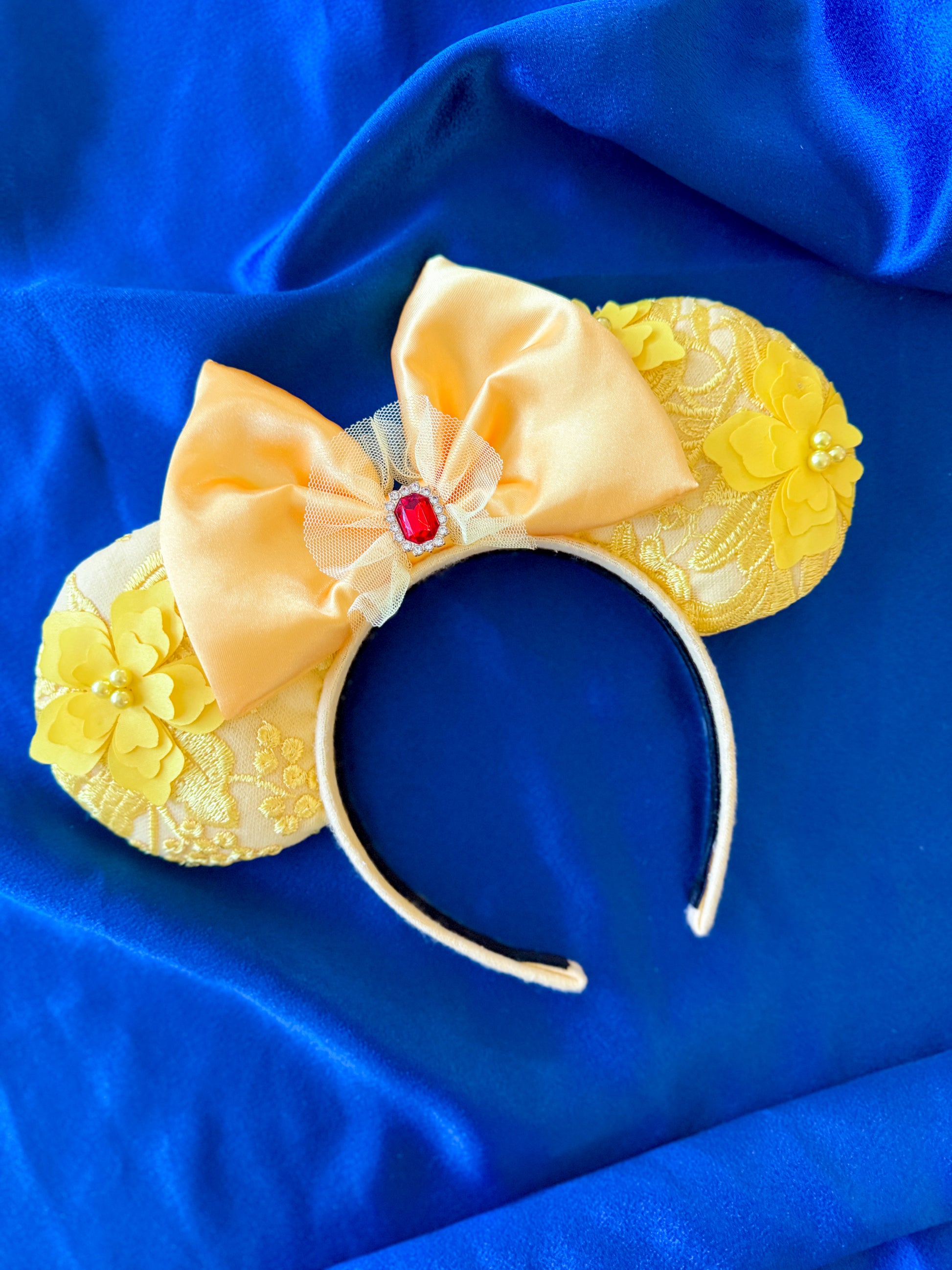 Yellow mouse ears with a bow and red gem on a blue background