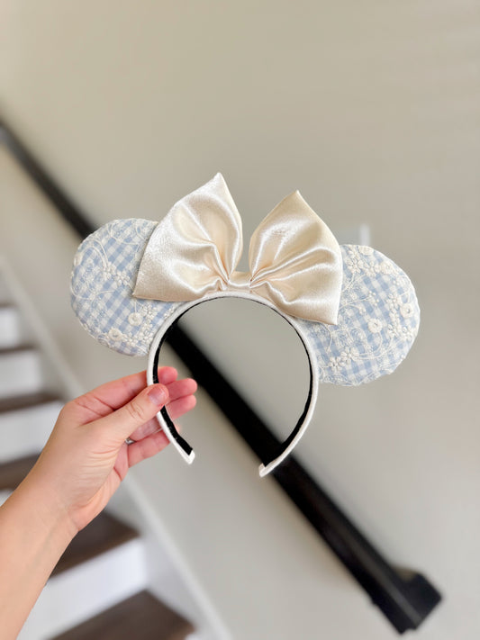 Mouse ear headband with a large bow held by a hand against a neutral background